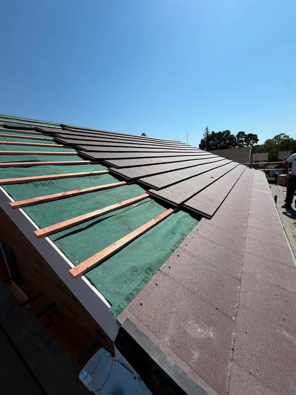 New concrete roof tiles being laid over breathable membrane and battens in Newbury