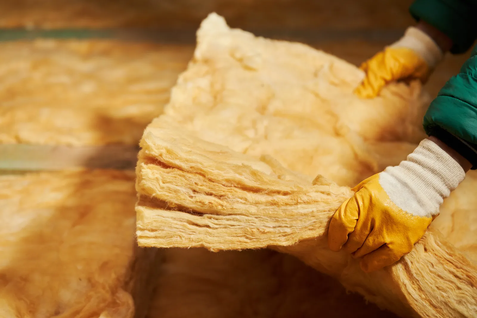 Loft insulation laying glass wool between joists