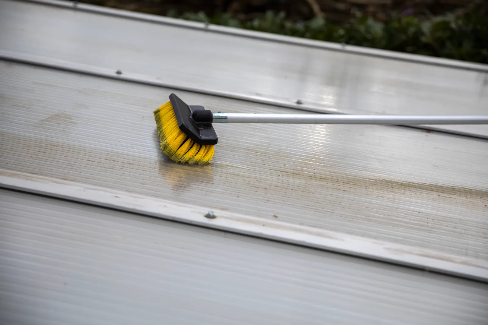 Roof cleaning soft wash brush on roof panel