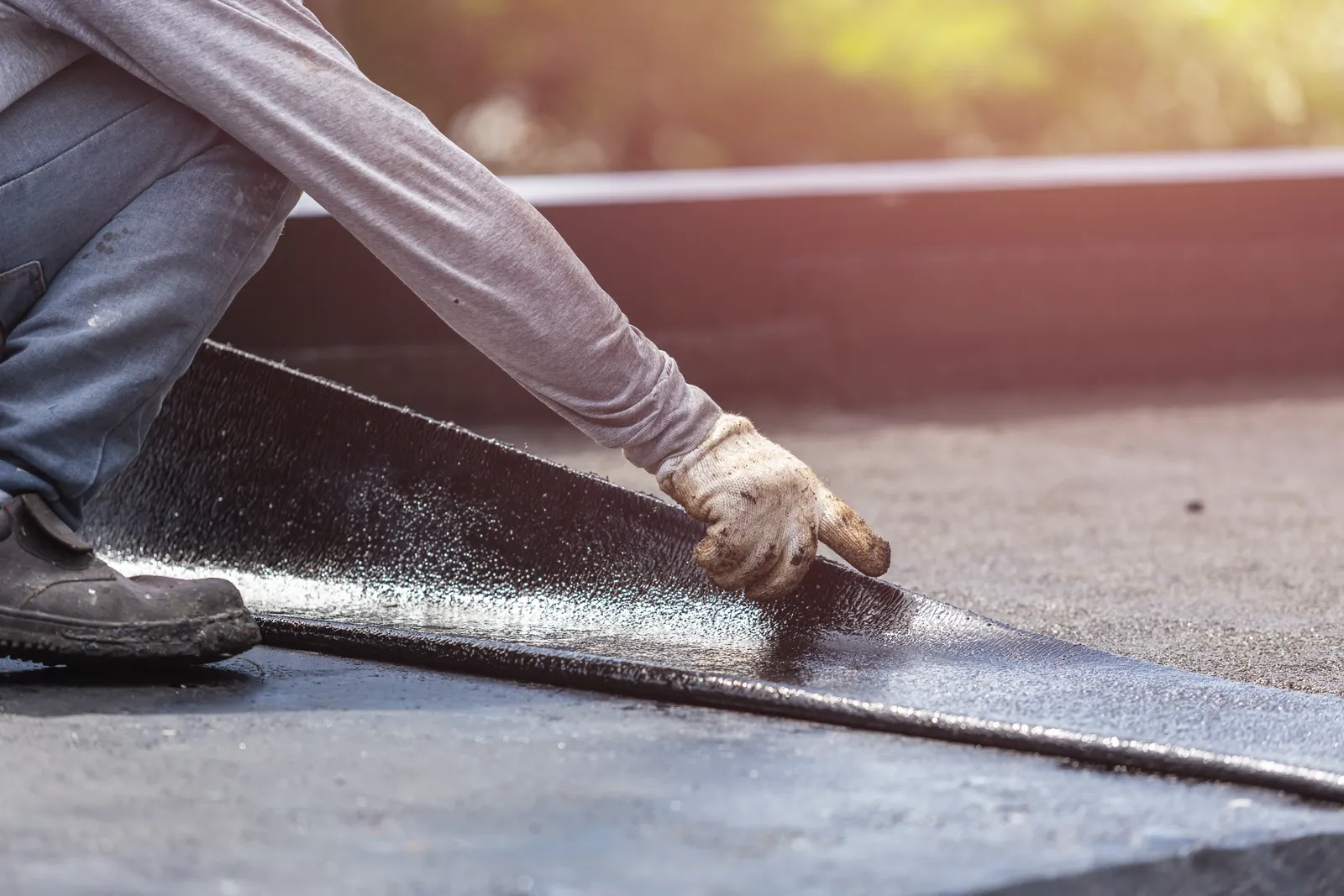 Flat roof roofer rolling out felt membrane closeup
