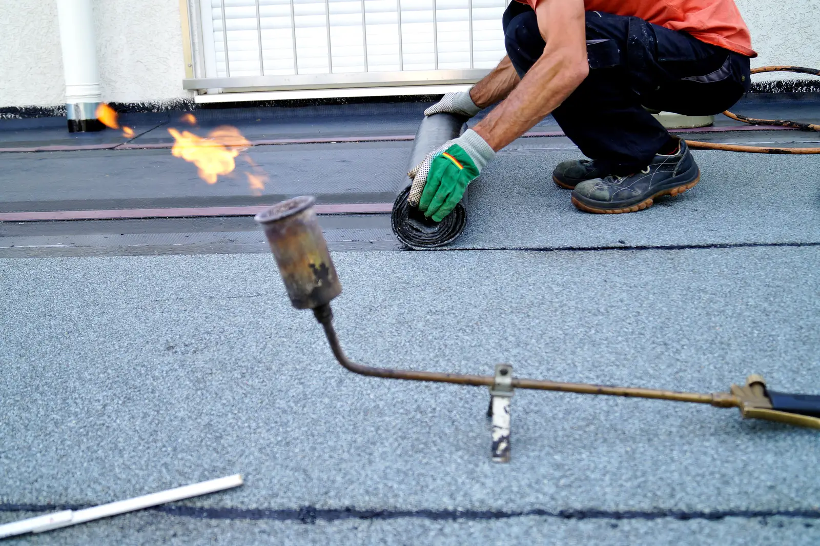 Flat roof roofer torch on felt membrane gas flame